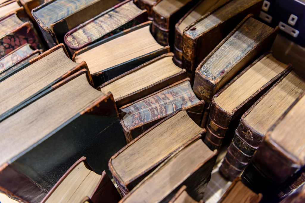 Close-up view of stacked antique Irish theology books with worn leather covers and marbled page edges.