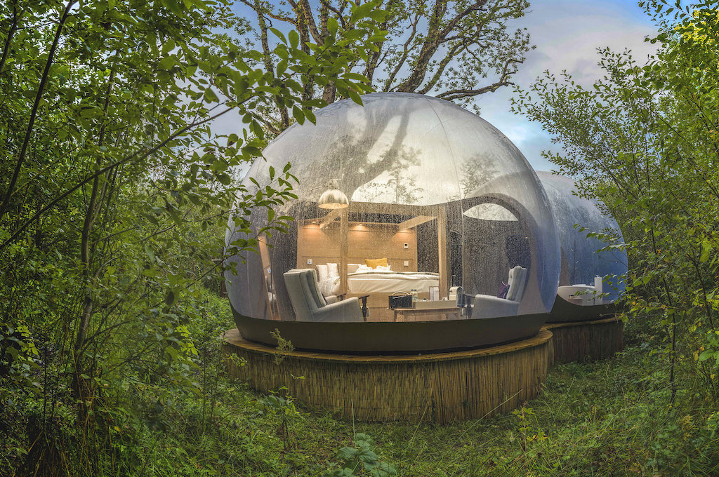 A clear dome glamping pod at Finn Lough, County Fermanagh, surrounded by forest and misted with rain.