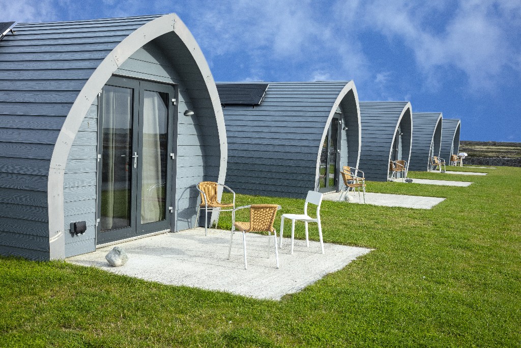 Grey glamping pods face open grass and the Atlantic at Aran Islands Camping and Glamping.