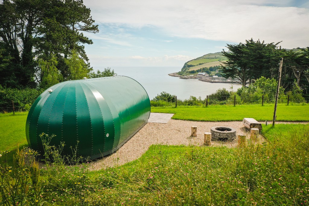 A modern green pod at Glenarm Castle, County Antrim, overlooking the sea and Causeway Coast cliffs.
