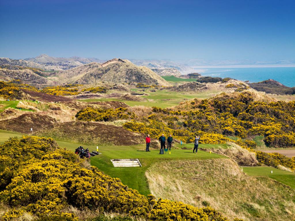 Royal County Down Golf Club, with golfers on scenic fairways framed by mountains and sea.