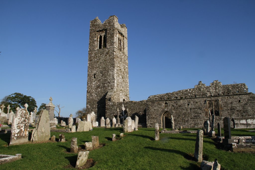 Hill of Slane with weathered gravestones scattered across the grassy cemetery under blue sky in Meath.