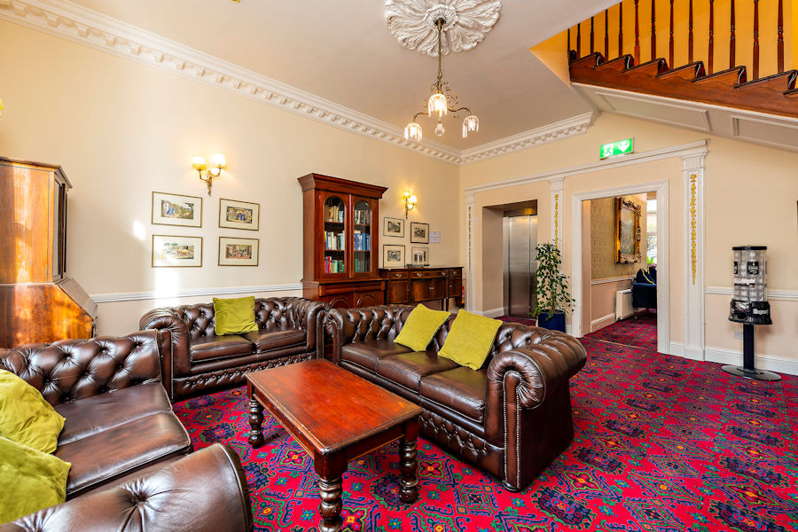 Traditional drawing room with leather sofas, wood furniture and red carpet in the Castle Hotel, Dublin.