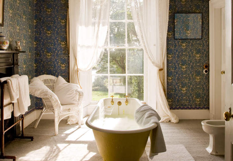 Vintage clawfoot bath under a tall window with white curtains in Hilton Park, Monagahan.