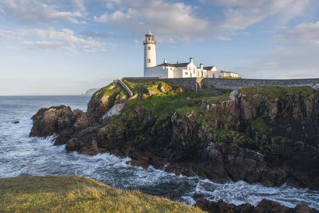 Fanad Head Lighthouse perched on a rocky headland above crashing waves on Donegal’s Fanad Peninsula.
