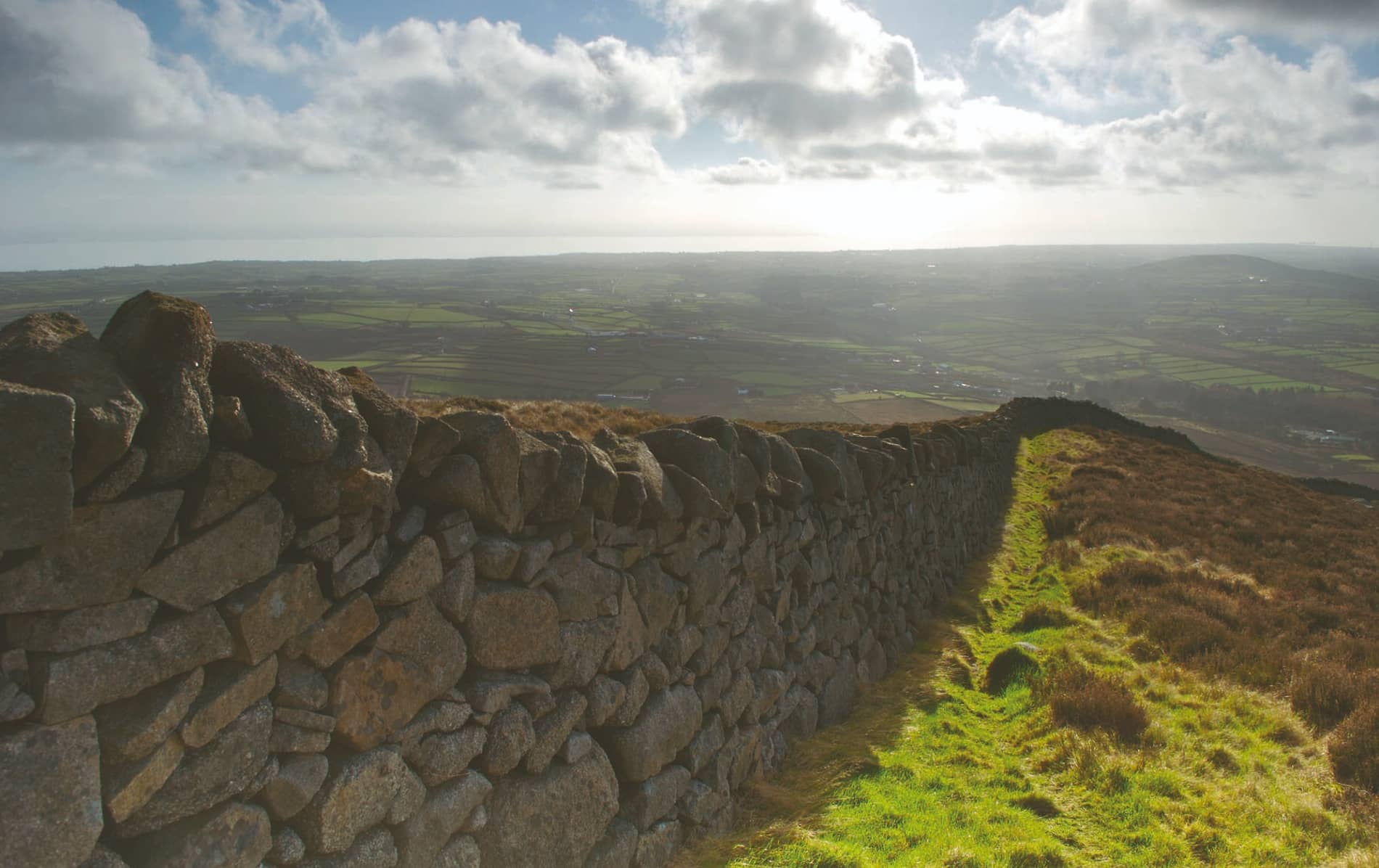 Stone Mourne Wall stretching over windswept hills with views of patchwork fields in County Down.