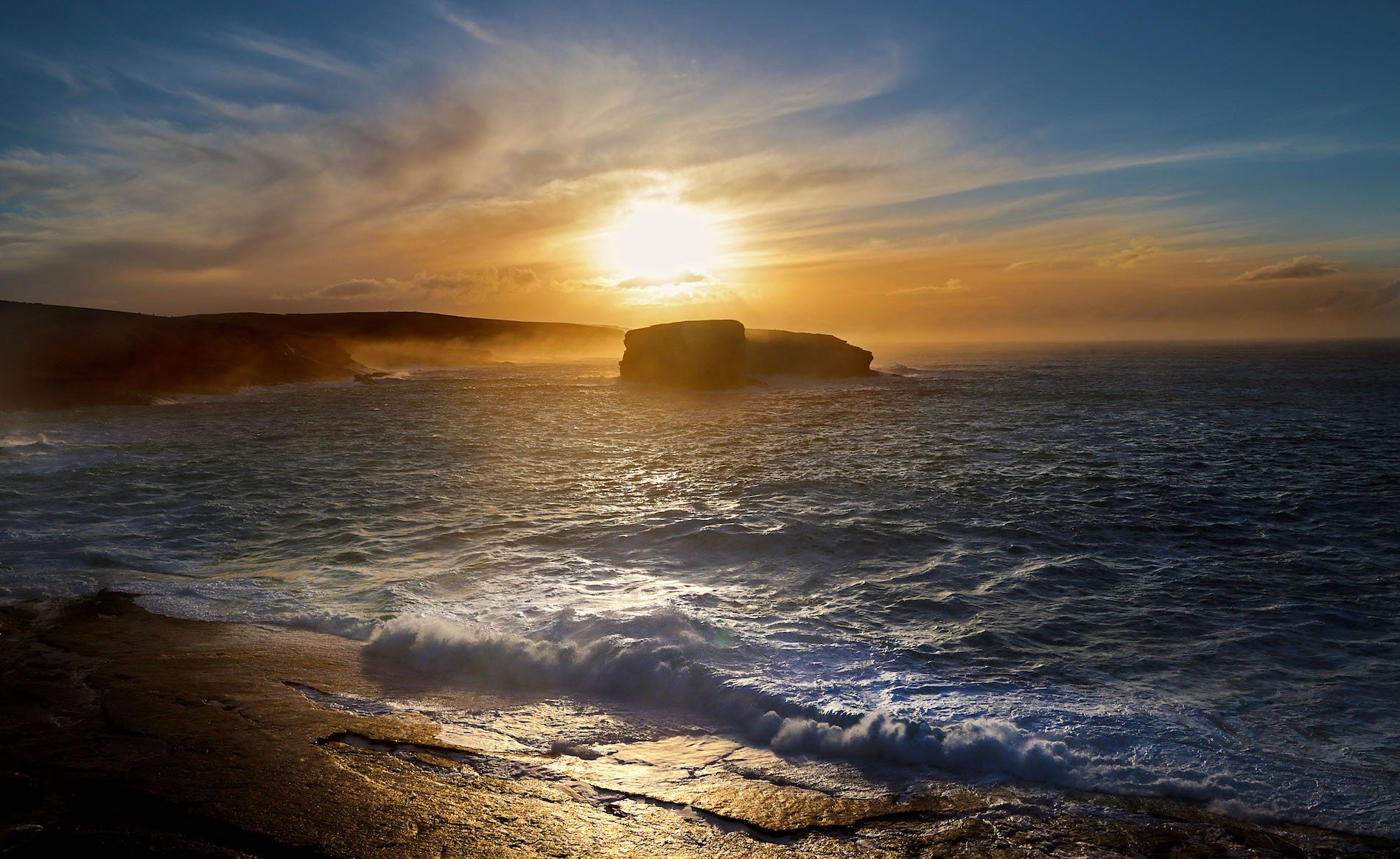 Golden sunset over misty cliffs and the Atlantic Ocean, capturing a serene moment along Ireland’s coastline.