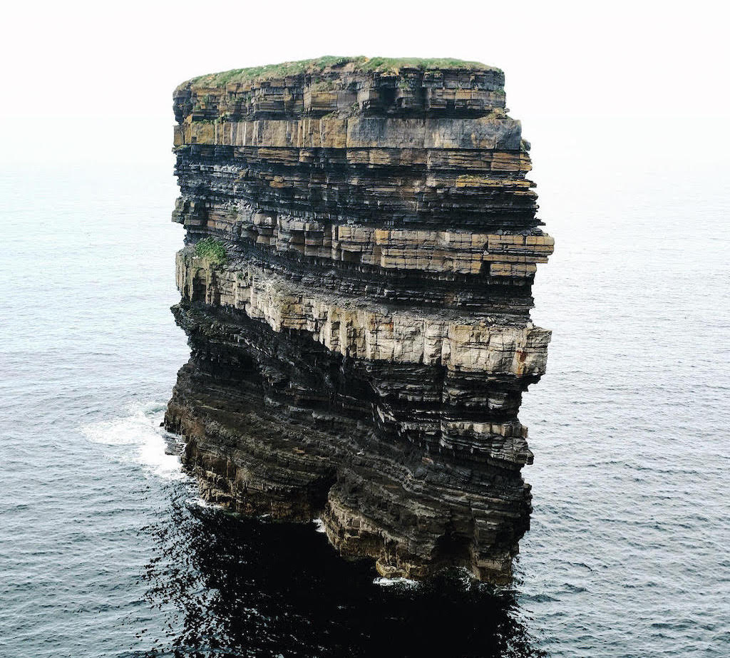 The towering sea stack of Downpatrick Head in County Mayo, its layered rock face rising from the Atlantic Ocean.