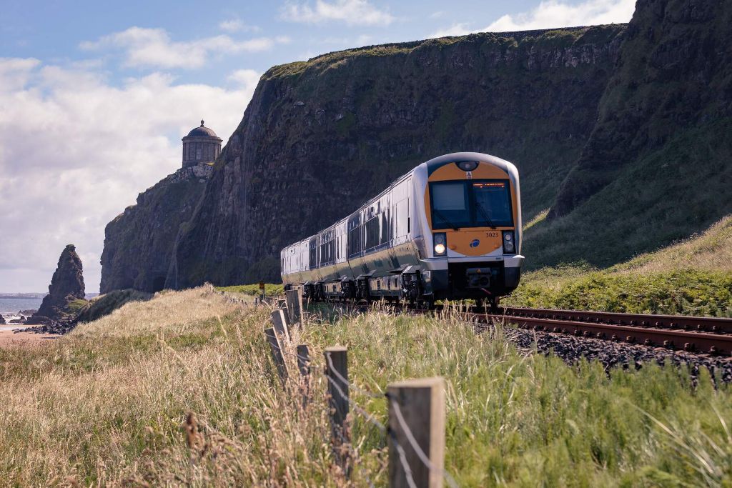 Train running past Mussenden Temple and cliffs along the Causeway Coast in Northern Ireland.