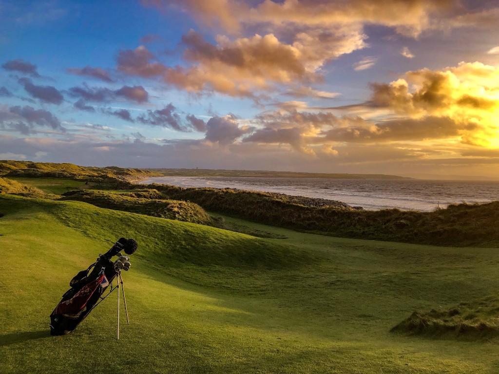 Golf bag on a coastal links course at sunset, representing Irish golfer Shane Lowry.
