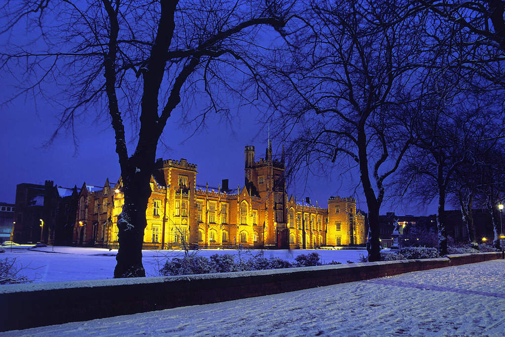 Queen’s University Belfast glowing warmly against a snowy winter evening.