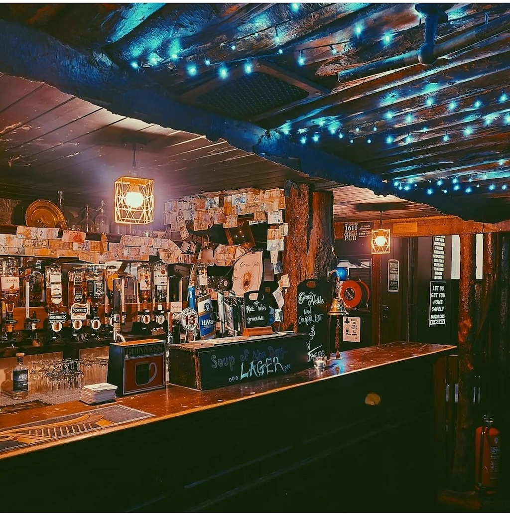 Rustic wooden bar with fairy lights and historic notes on display inside Grace Neill’s pub in Donaghadee, County Down.