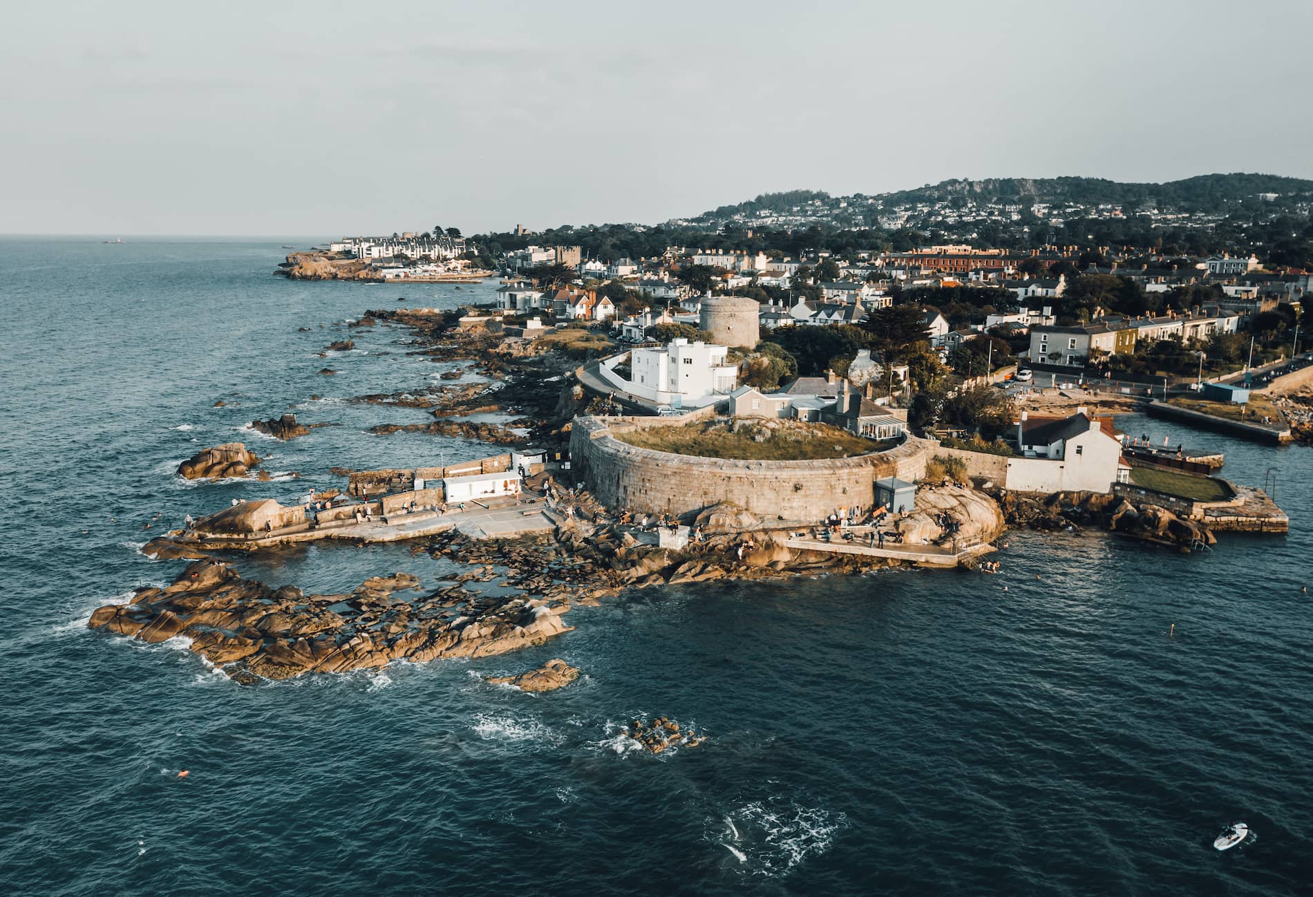 Aerial view of James Joyce Tower and Museum in Sandycove, County Dublin, with rocky coastline and surrounding homes.