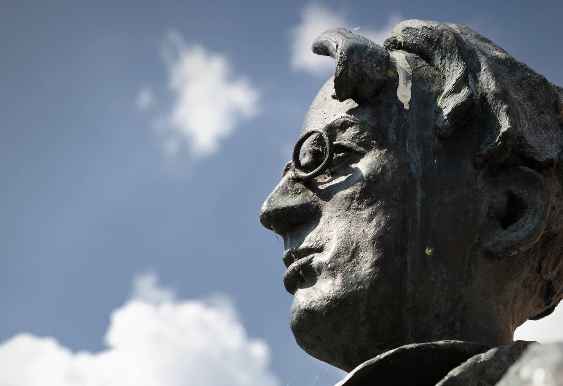 Close-up of bronze WB Yeats statue in Sligo, showing poet’s distinctive profile against a blue sky with scattered clouds.