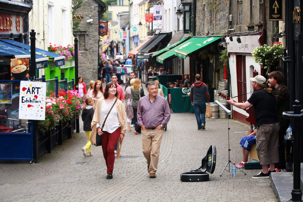 Visitors strolling along Kilkenny’s Medieval Mile with street musicians performing.