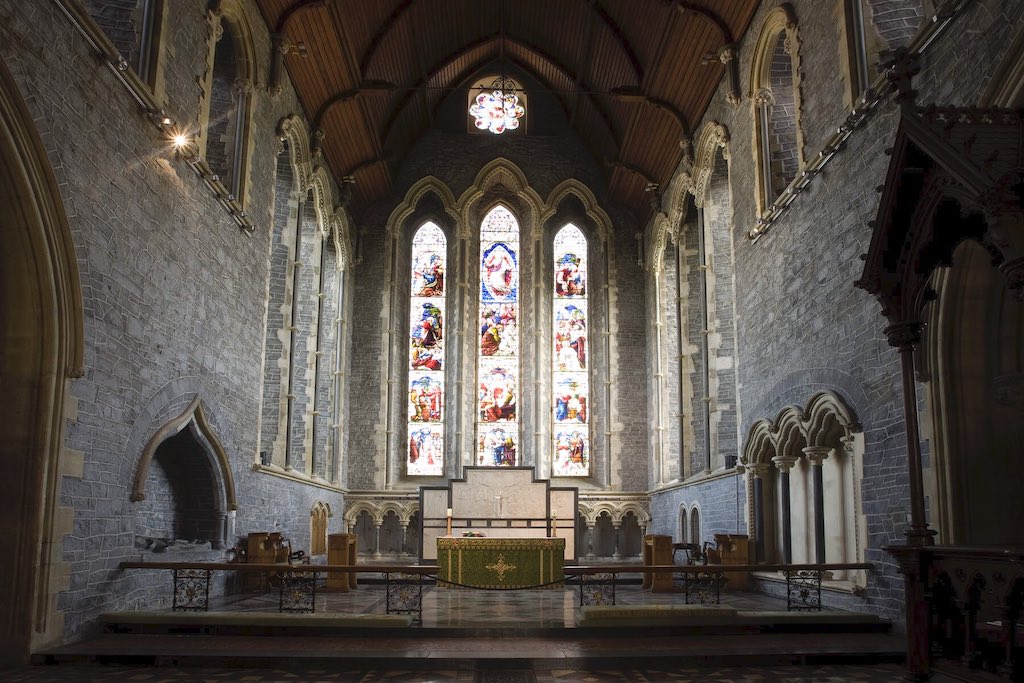 Interior of St Canice’s Cathedral with stained glass windows and stone arches.