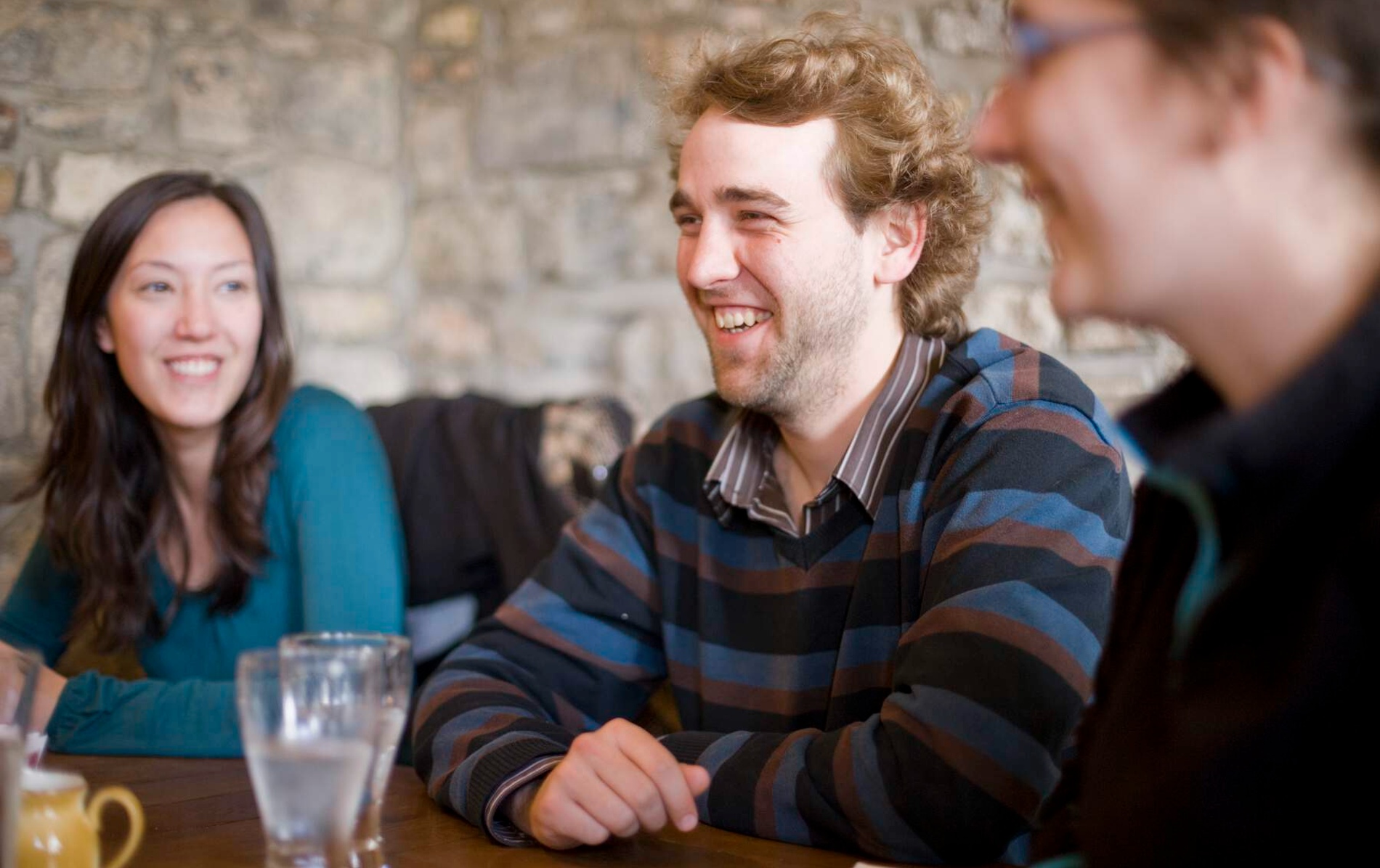 Group of friends laughing and chatting inside a stone-walled pub in Limerick.
