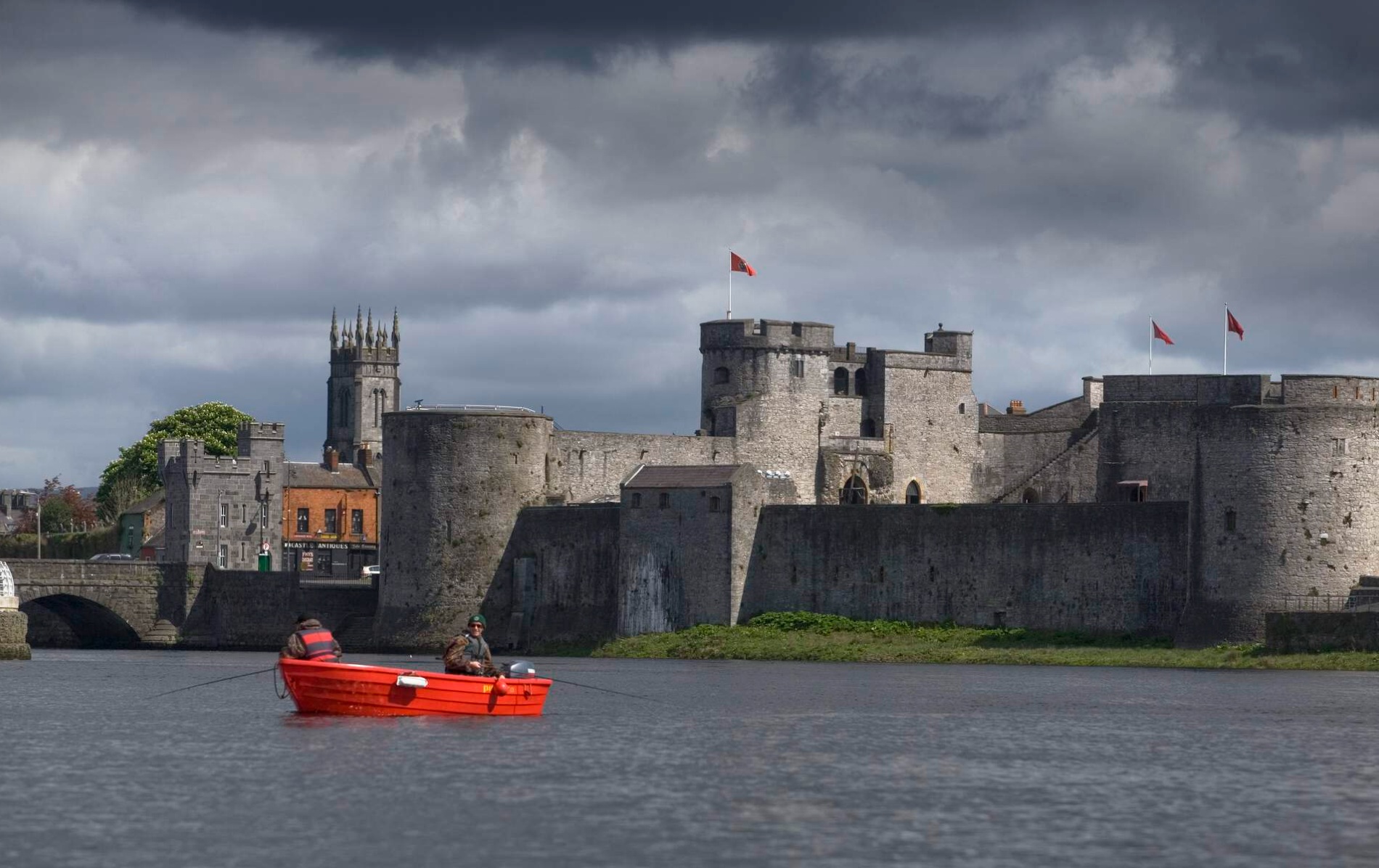 Fishermen in a red boat on the River Shannon with King John’s Castle in the background.