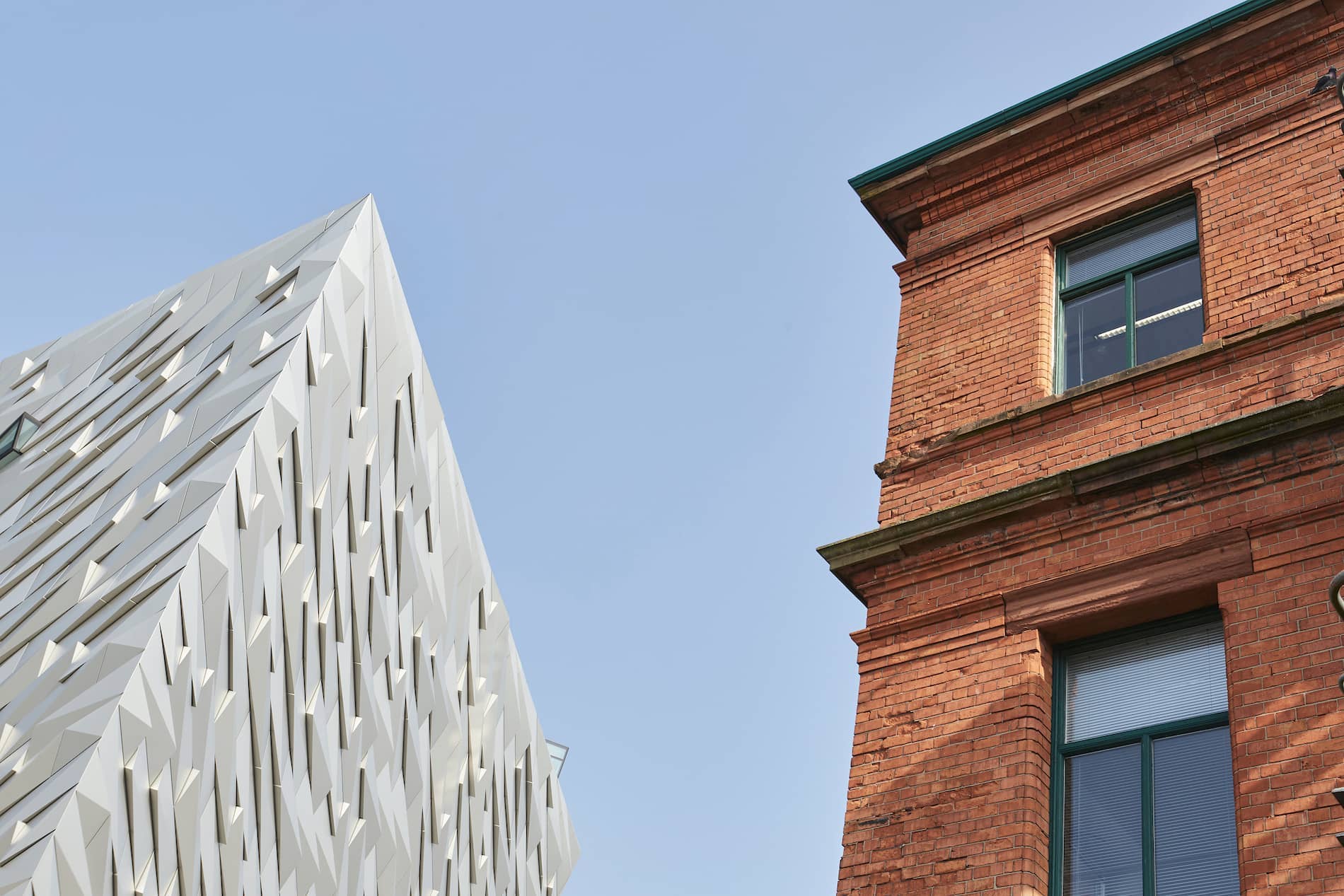 Titanic Belfast’s angular façade beside the red-brick Harland and Wolff offices, now the Titanic Hotel.