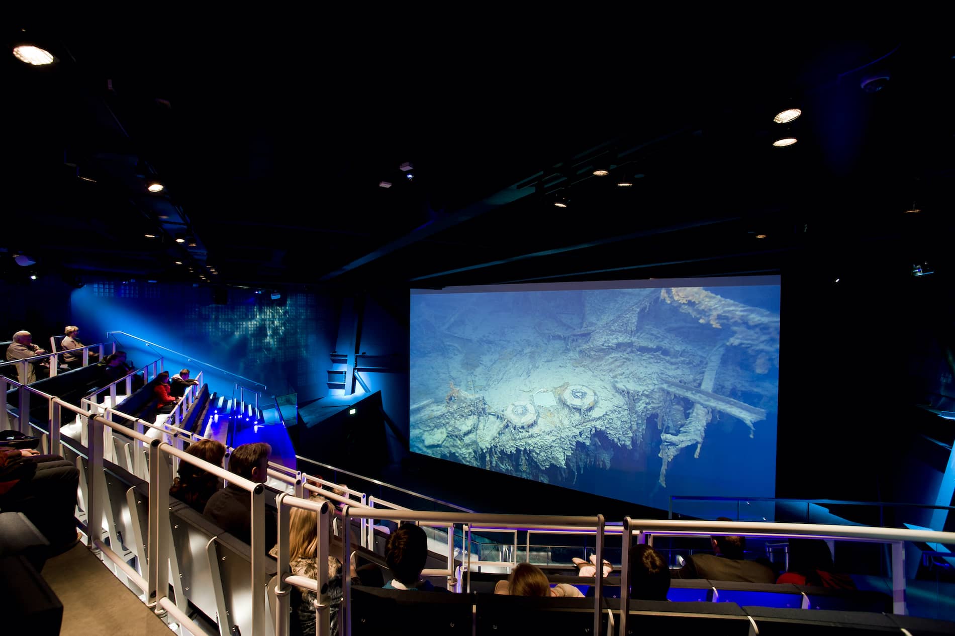 Visitors watch footage of the Titanic wreck in a dimly lit theatre at Titanic Belfast.