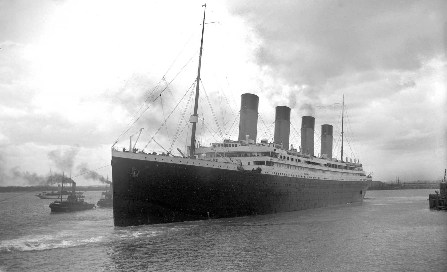 RMS Titanic departing Southampton, with smoke billowing from its funnels as it sails into open water.