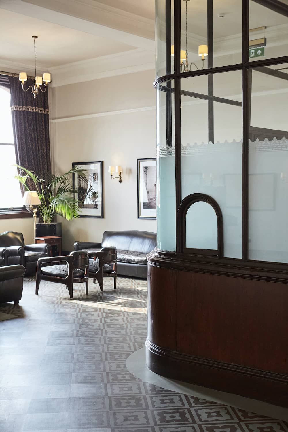 Vintage booth and leather armchairs in the Titanic Hotel, Belfast, with framed photos and soft lighting.