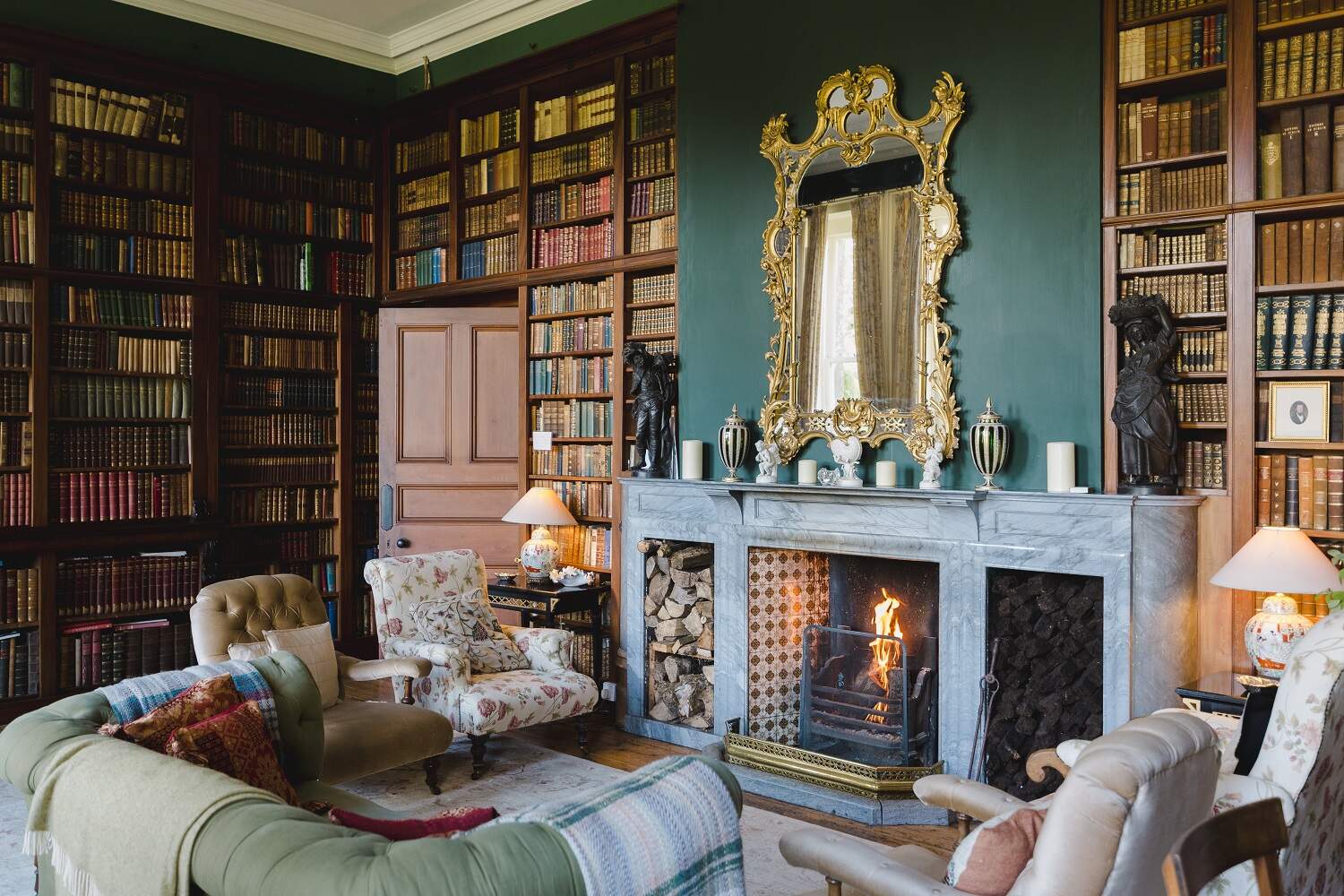 Opulent library lounge with fireplace, gilt mirror, and shelves of antique books at Clonalis House, County Roscommon.