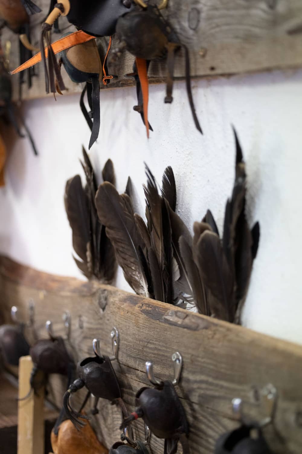 Dark feathers and traditional falconry hoods hanging on hooks at Ashford Castle’s School of Falconry.