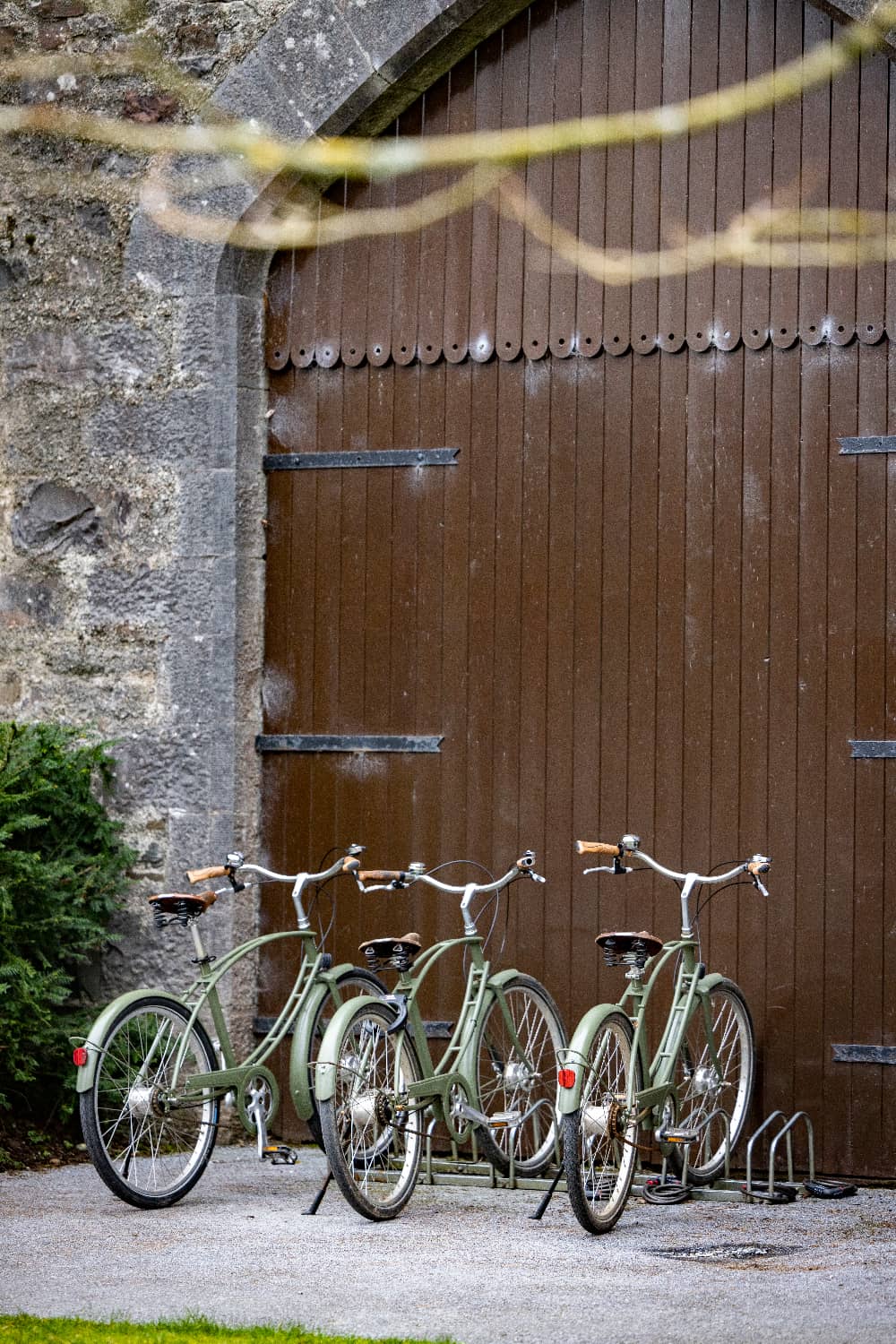 Vintage-style green bicycles parked outside a wooden stable door at Ashford Castle, County Mayo.