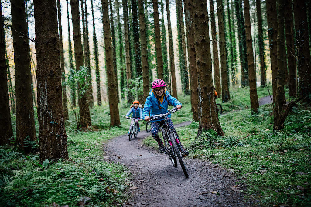 Two children cycle along a dirt trail through Gosford Forest Park at a family-friendly greenway in Armagh.