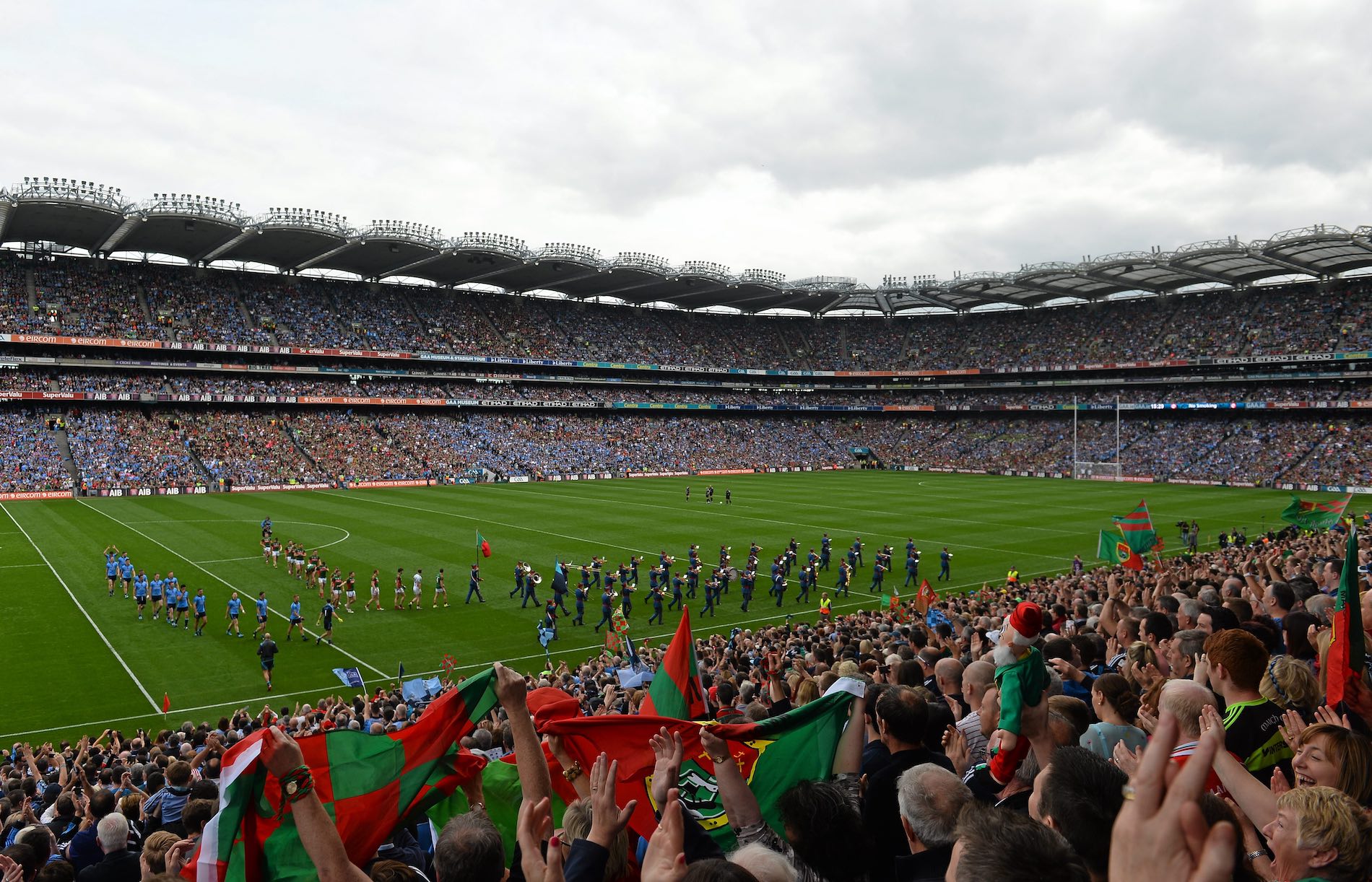 Fans wave red and green flags in a packed Croke Park stadium during a Gaelic football final in Dublin.