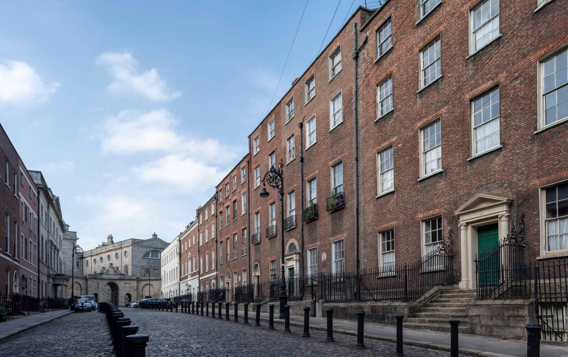Georgian brick buildings on Henrietta Street, Dublin, under a blue sky with scattered clouds.