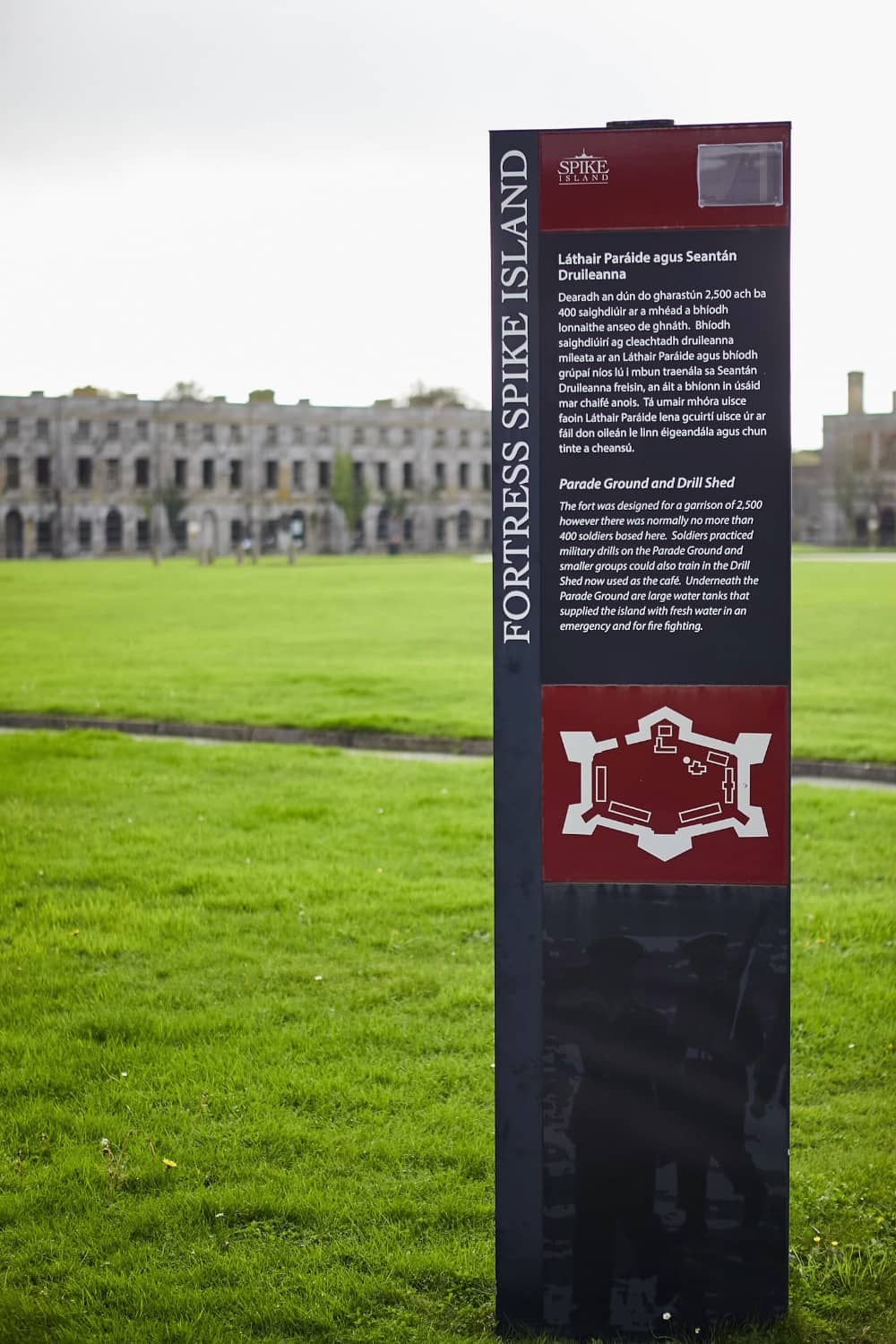 Information sign for Fortress Spike Island with parade ground in the background.