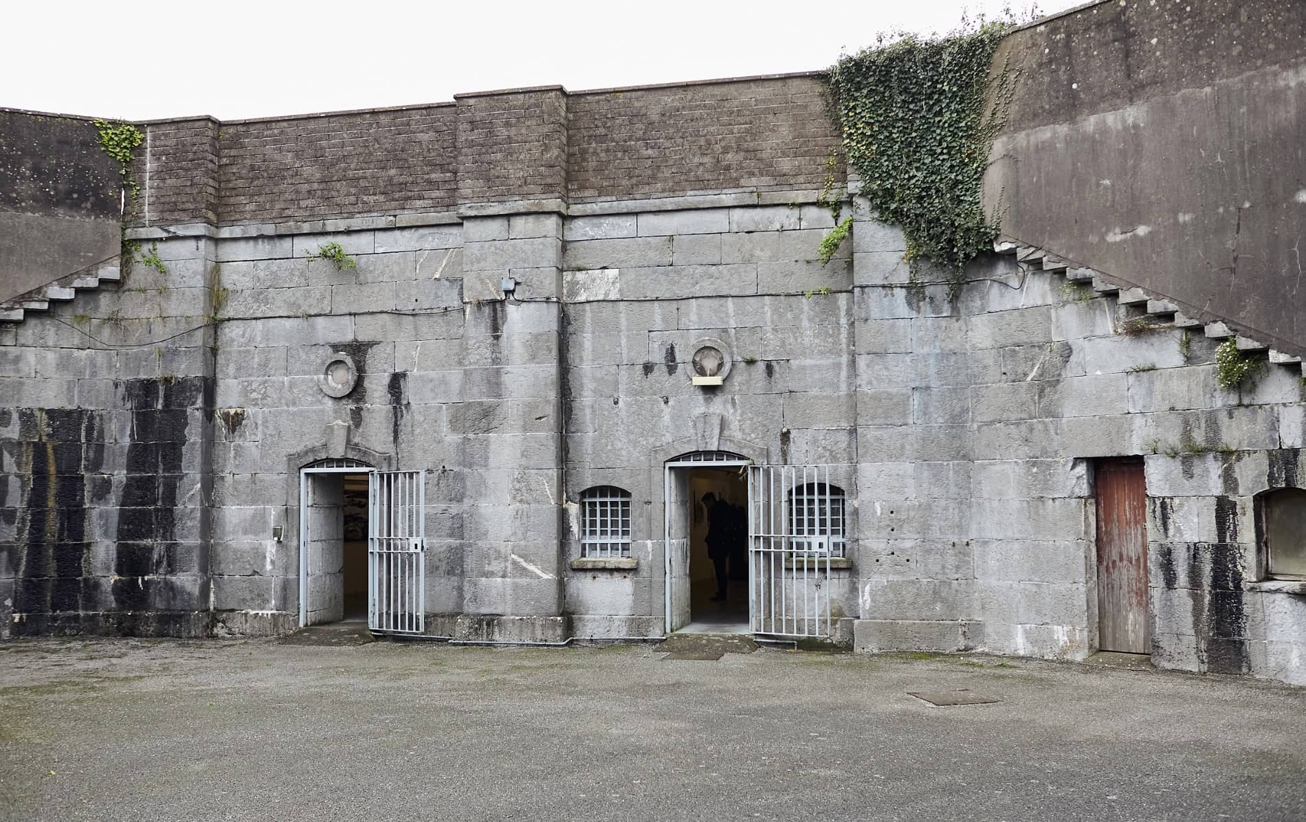 Grey stone prison building with barred doors at Spike Island, County Cork.