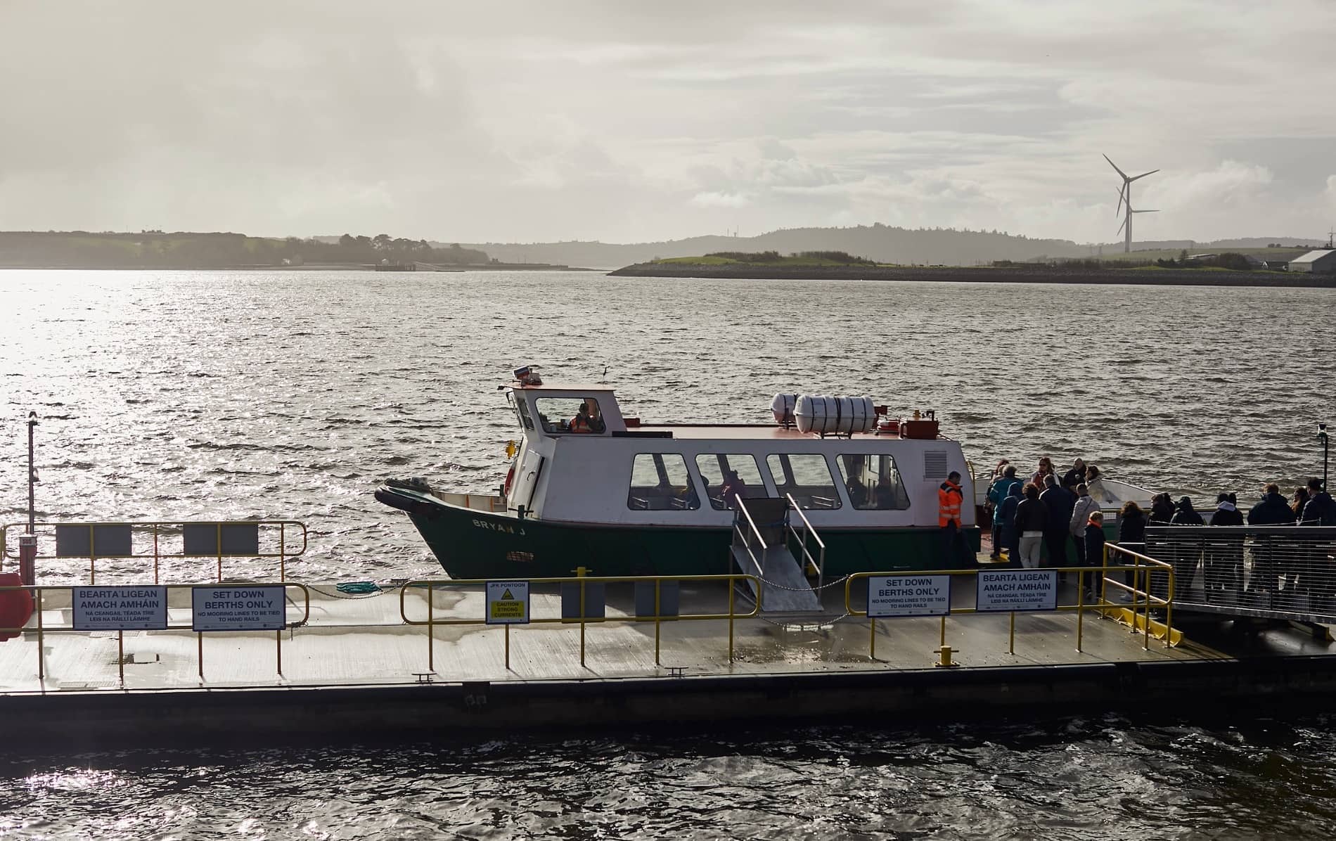 Passenger ferry docked at a pier with people boarding for the trip to Spike Island.