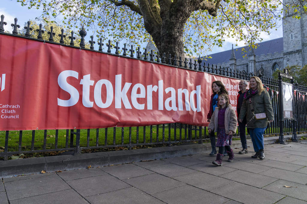 Family walking past a red Stokerland festival banner in Dublin city.
