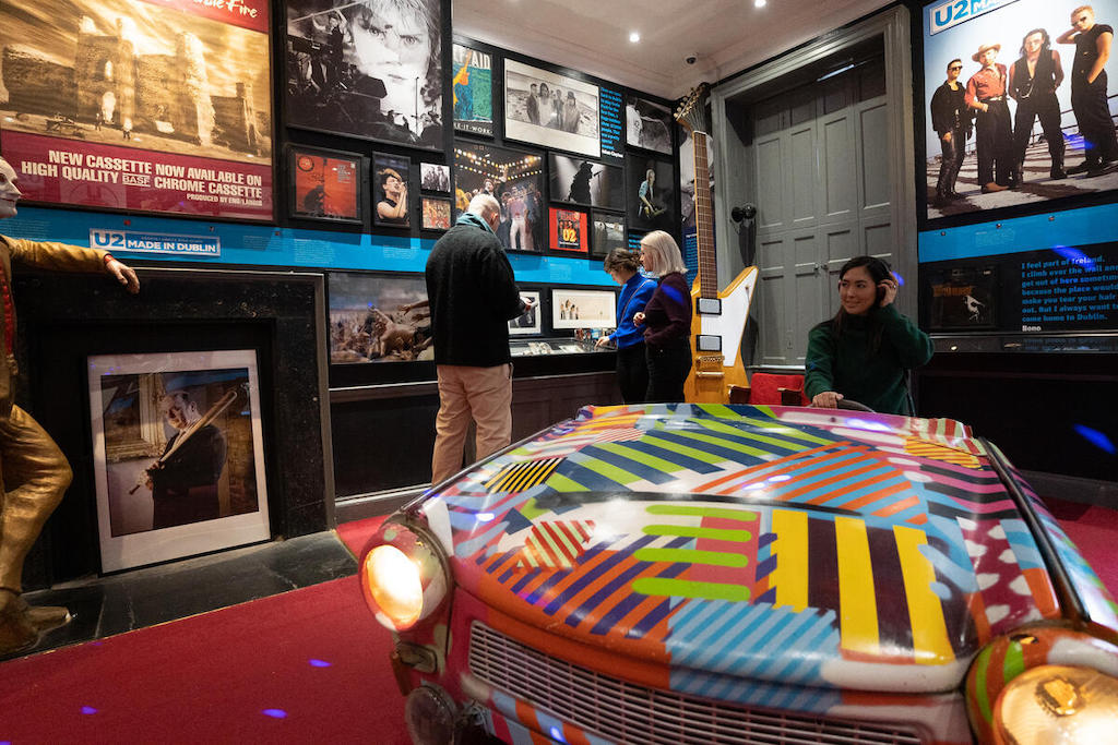Visitors exploring music exhibits inside the Little Museum of Dublin, with framed memorabilia and displays on the walls.