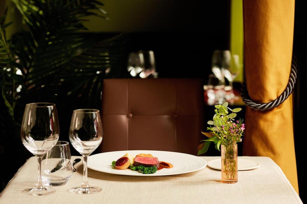 Elegant fine dining table set with a plated gourmet dish, wine glasses and soft lighting in a Michelin-star restaurant in Ireland.