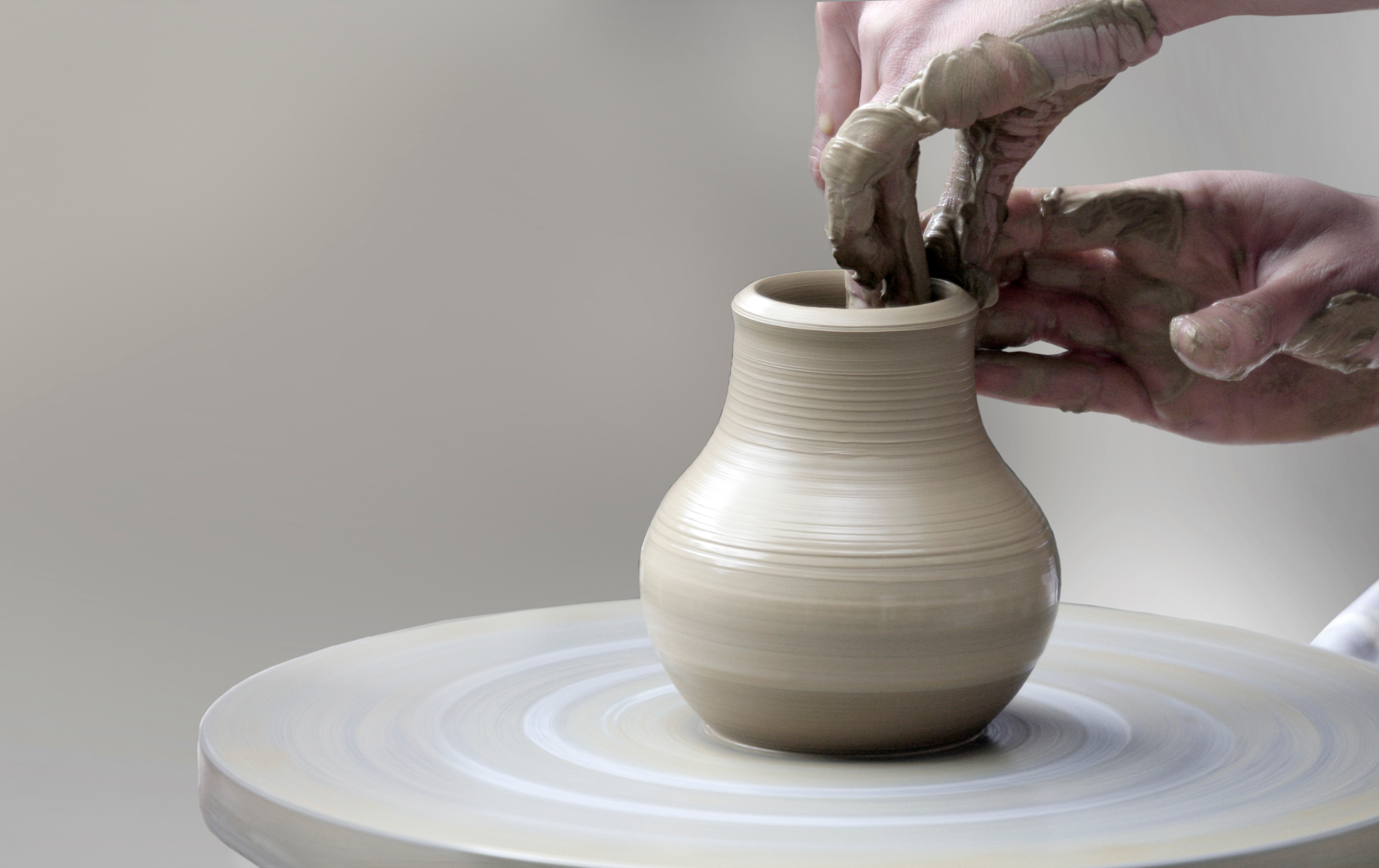 Hands shaping a clay pot on a pottery wheel in an Irish craft workshop.