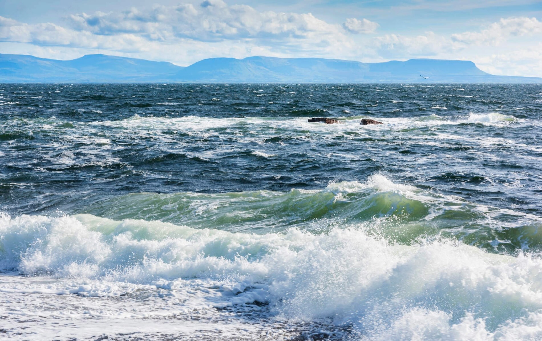 Waves crashing on the shore at Muckross in County Donegal, with mountains in the distance.