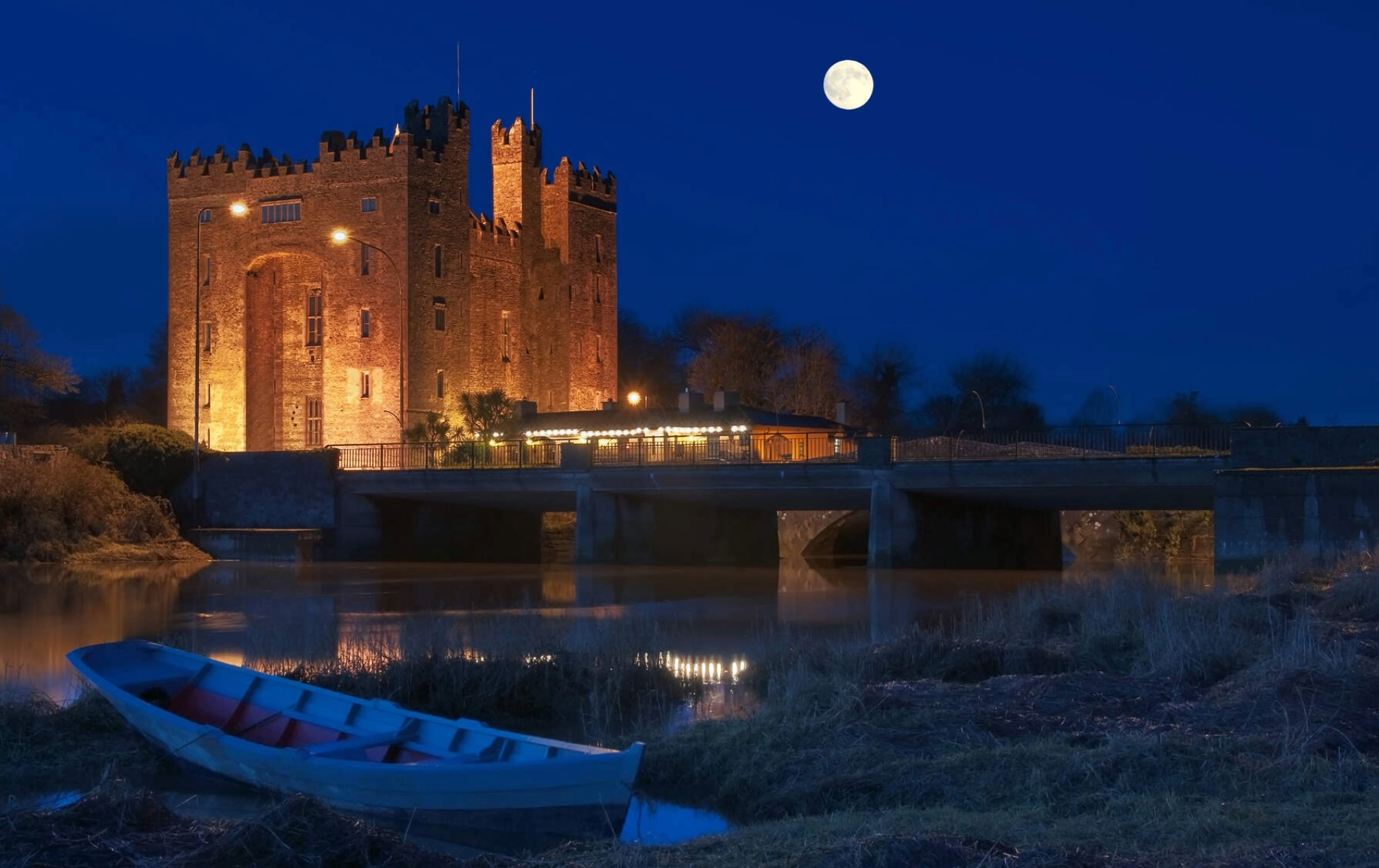 Bunratty Castle illuminated at night beside the River Shannon in County Clare, Ireland.