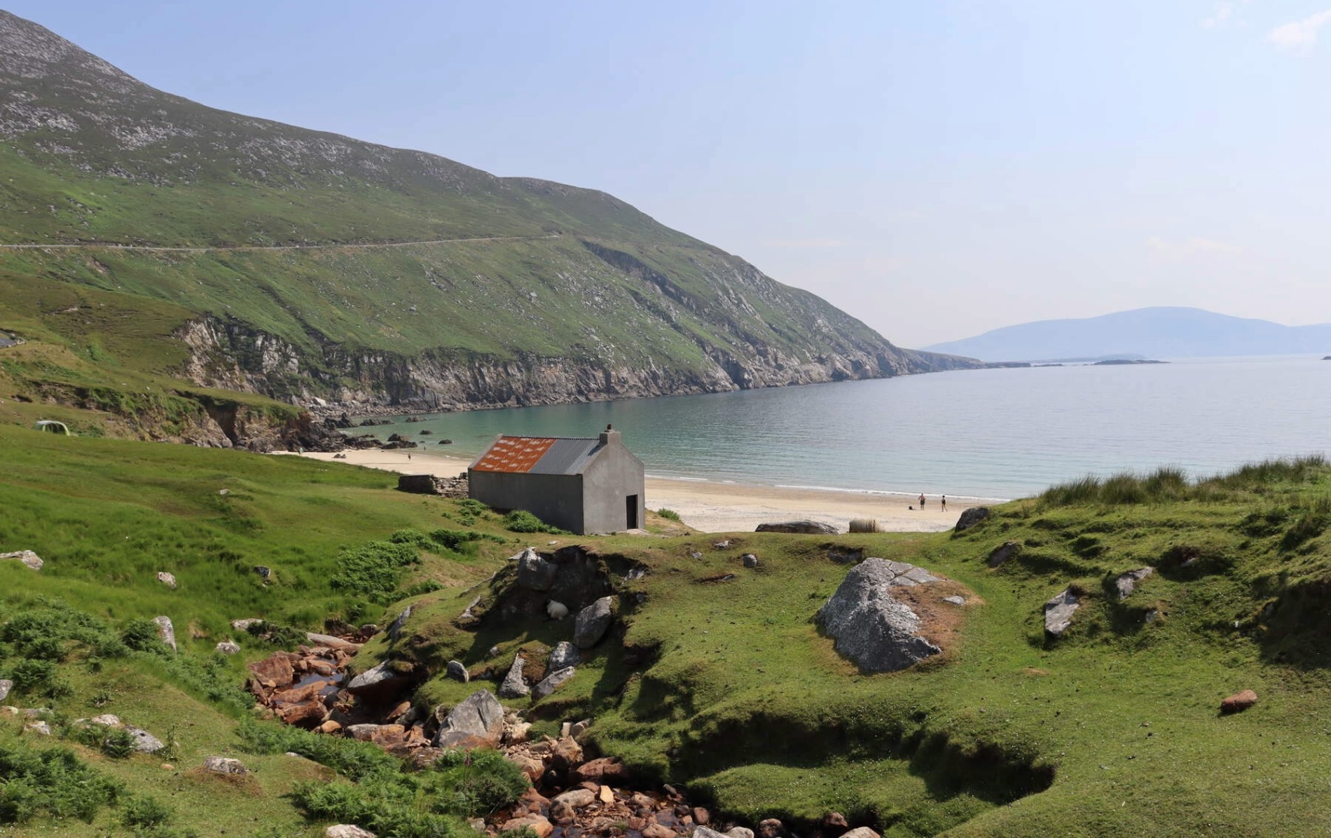 Cottage by Keem Bay beach on Achill Island, County Mayo, surrounded by green hills and cliffs.