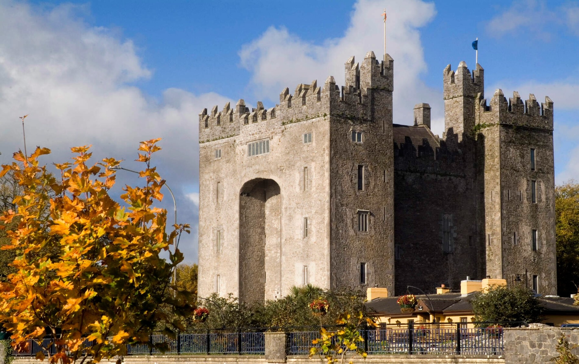 Bunratty Castle in County Clare, Ireland, with golden autumn leaves in the foreground.