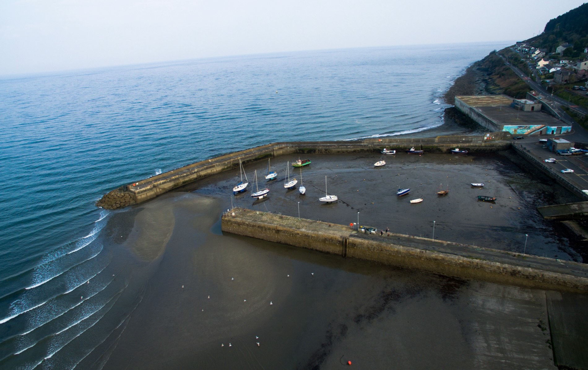 Fishing boats resting on the sand at Newcastle Harbour in County Down, at low tide.