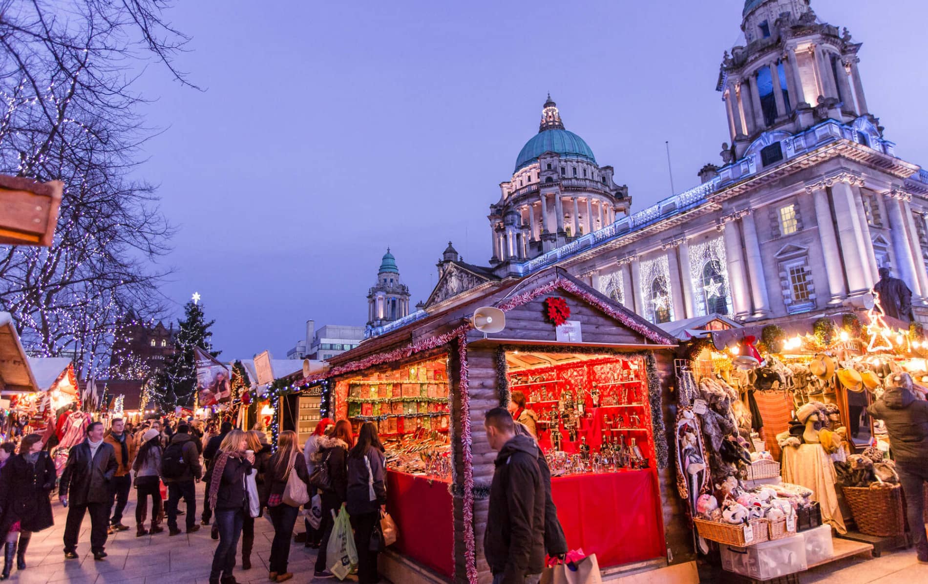 Crowds exploring festive Christmas market stalls outside Belfast City Hall.