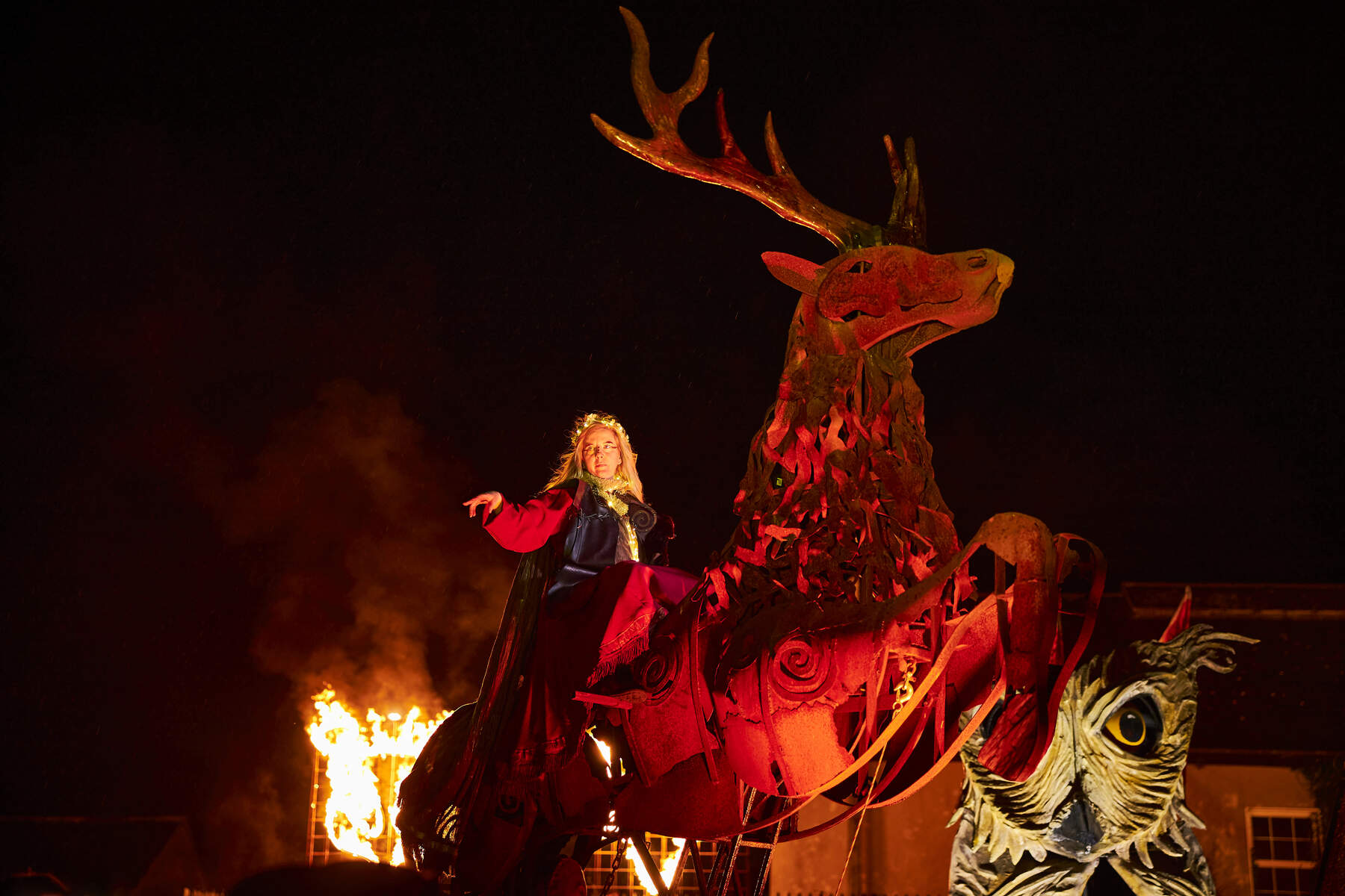 Performer in a cloak rides flaming antlered creature at night-time Samhain Festival in County Longford.