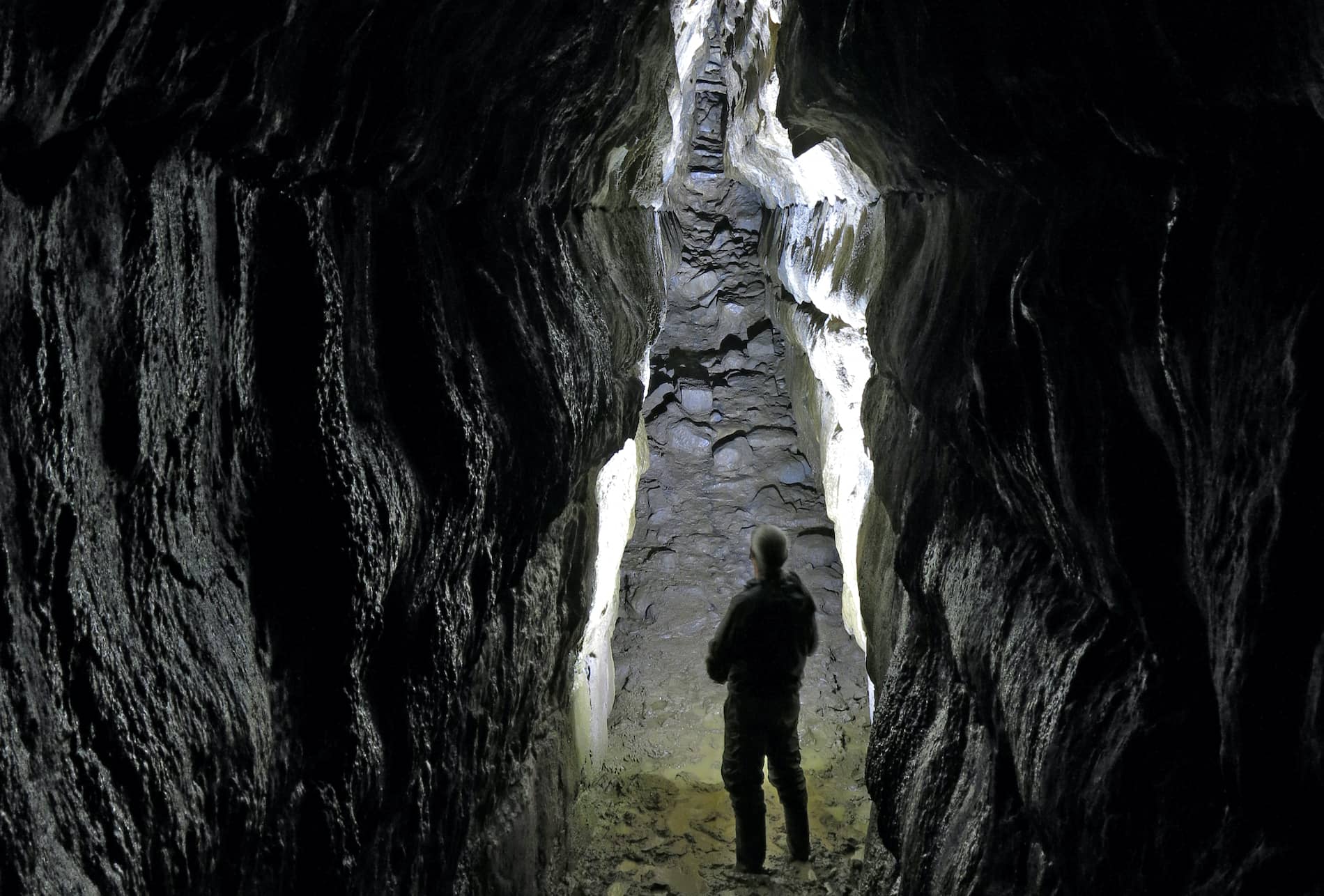 Person standing inside the dark limestone passages of Oweynagat Cave in County Roscommon.