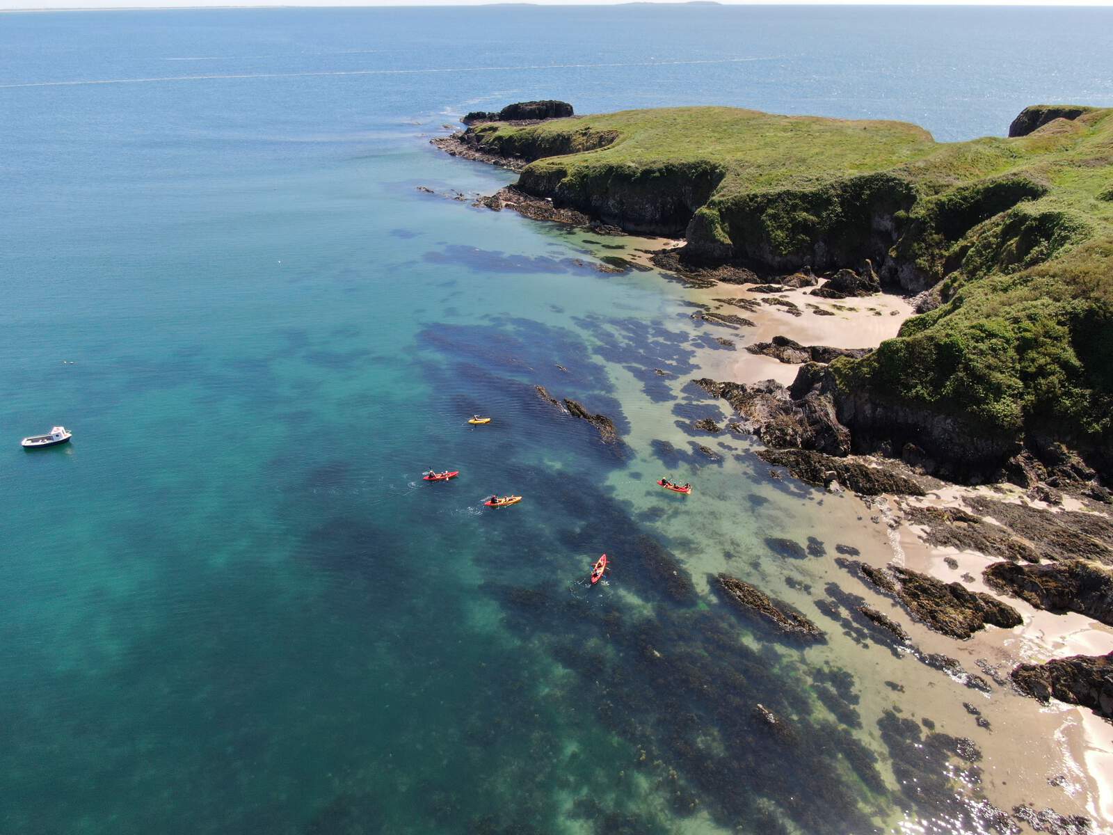 Kayakers paddling along the rocky coastline and clear waters of County Wexford.