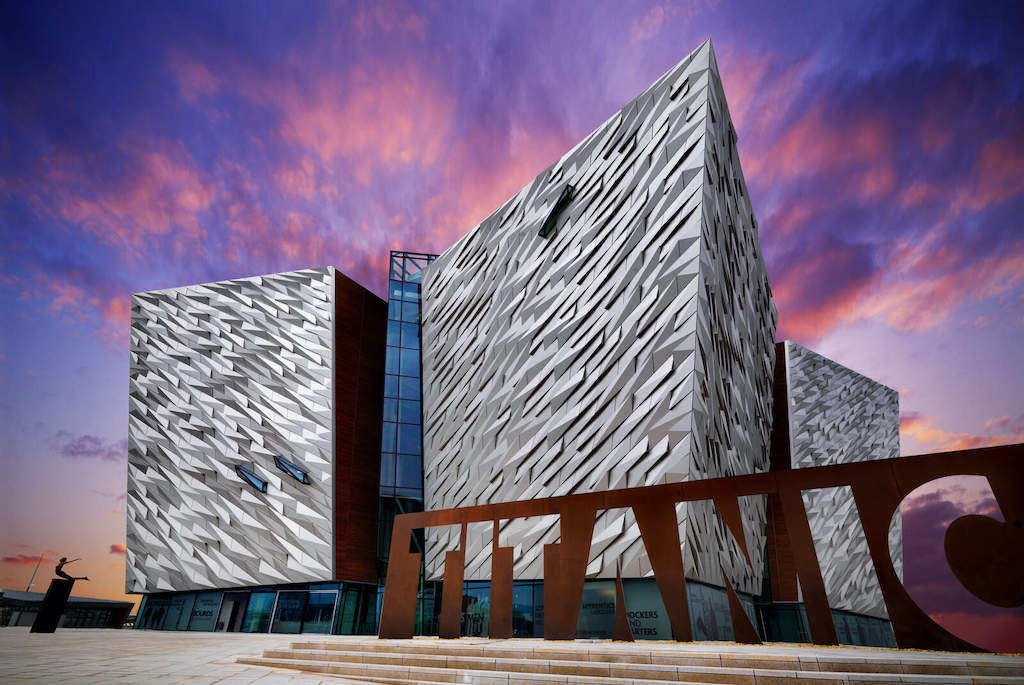 Striking modern façade of Titanic Belfast museum under a vivid purple and pink evening sky.