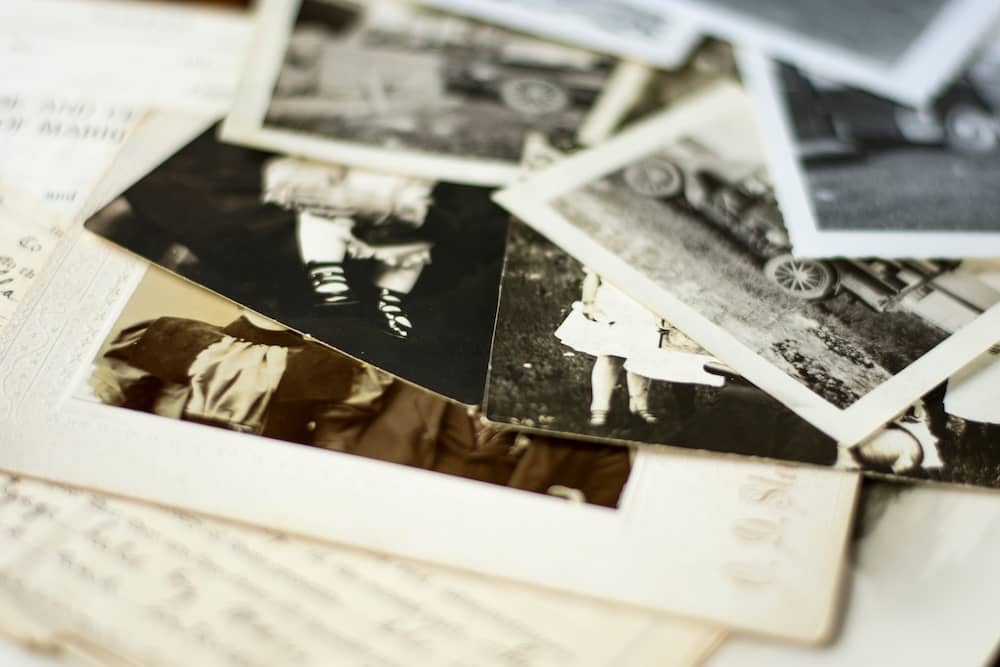 Scattered vintage black-and-white family photographs laid out on top of handwritten documents.